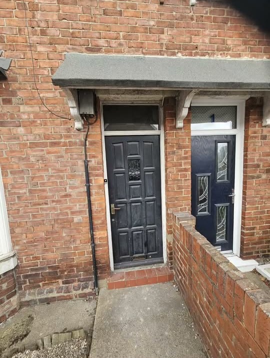 Two new black composite front doors on a red brick terrace