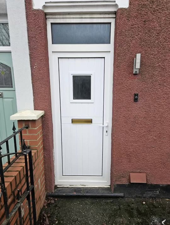 New white uPVC stable-style front door with a top light on a red rendered house
