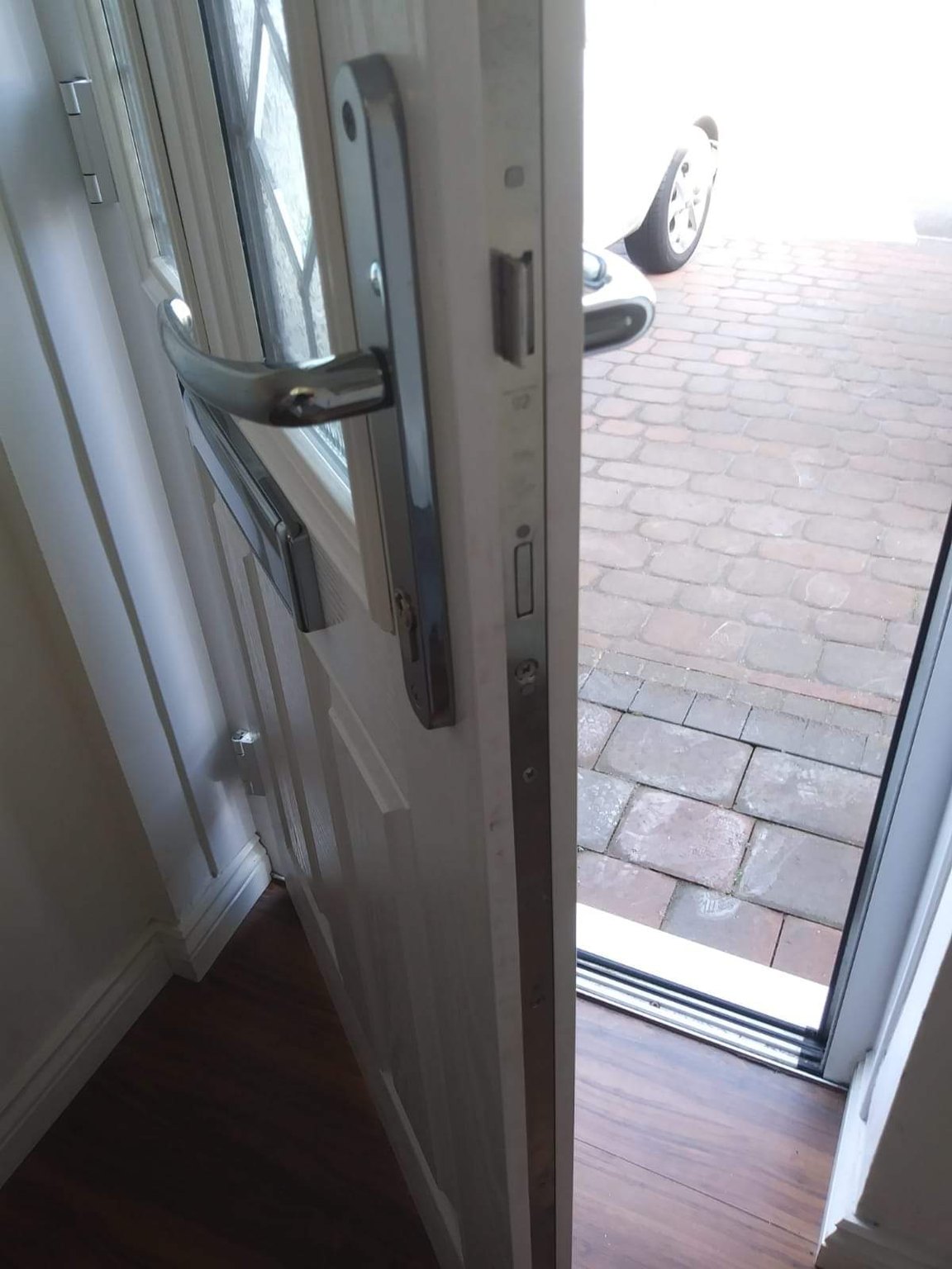 Open uPVC door showing the multipoint lock mechanism, with a block-paved drive outside