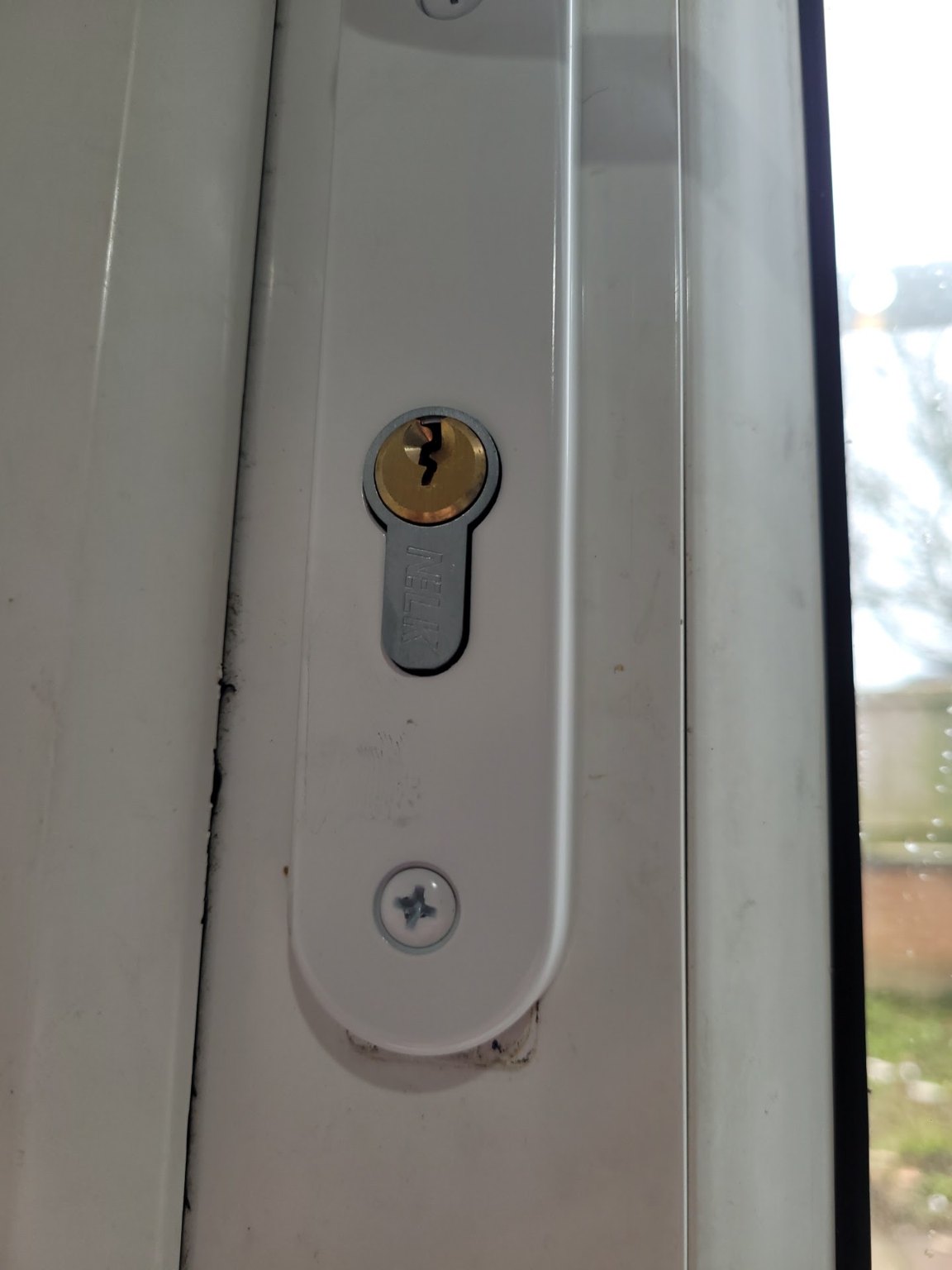 Close-up of a new brass euro cylinder fitted in a white uPVC door